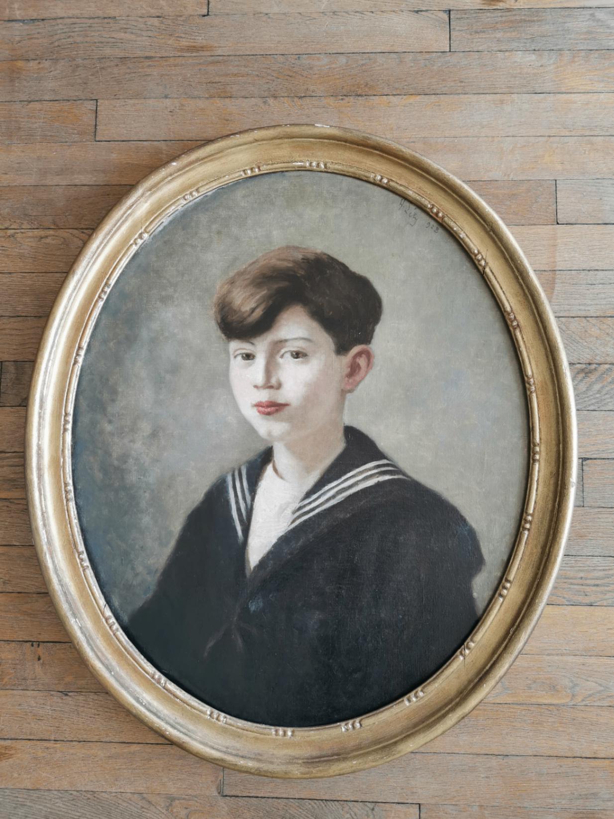 Antique portrait in a gilded oval frame, placed on a parquet floor